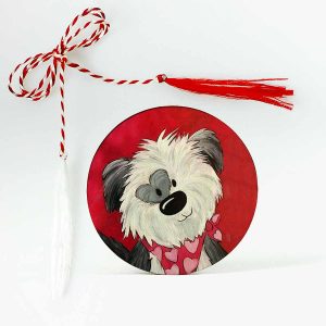 Imagine cu un mărțișor din lemn personalizat, ilustrând un cățel alb pe un fundal roșu vibrant. Cățelul are o pată în formă de inimă în jurul unui ochi, adăugând un detaliu adorabil și unic.