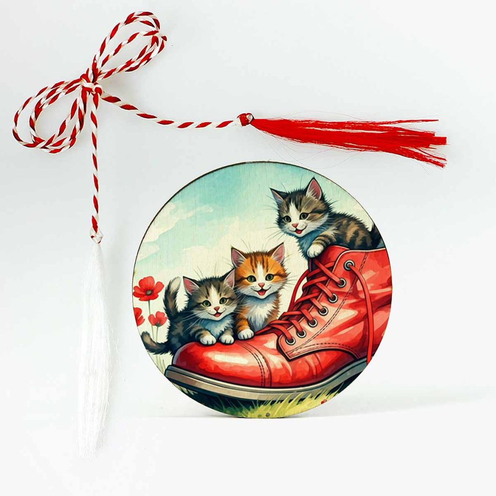 Imagine cu un mărțișor din lemn personalizat, ilustrând trei pisicuțe jucăușe într-un pantof mare roșu, cu șiretul desfăcut. Un design drăgălaș și plin de energie, perfect pentru a adăuga un strop de distracție primăverii.