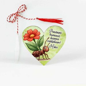 Mărțișor din lemn în formă de inimă, tip broșă, personalizat cu mesajul „O primăvară frumoasă, doamna educatoare/invățătoare”, și o furnicuță care cară o floare mare roșie, simbol al muncii și al primăverii.