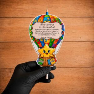 Cadou pentru prima zi de școală cu creion inclus și suport personalizat din carton 250 g, în formă de balon cu aer cald, personalizat cu mesaj, clasa și anul școlar.